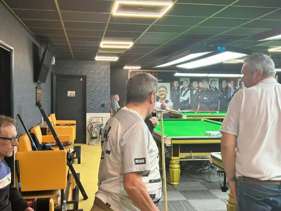 Players and spectators gathered by a table beneath a mural of professional players