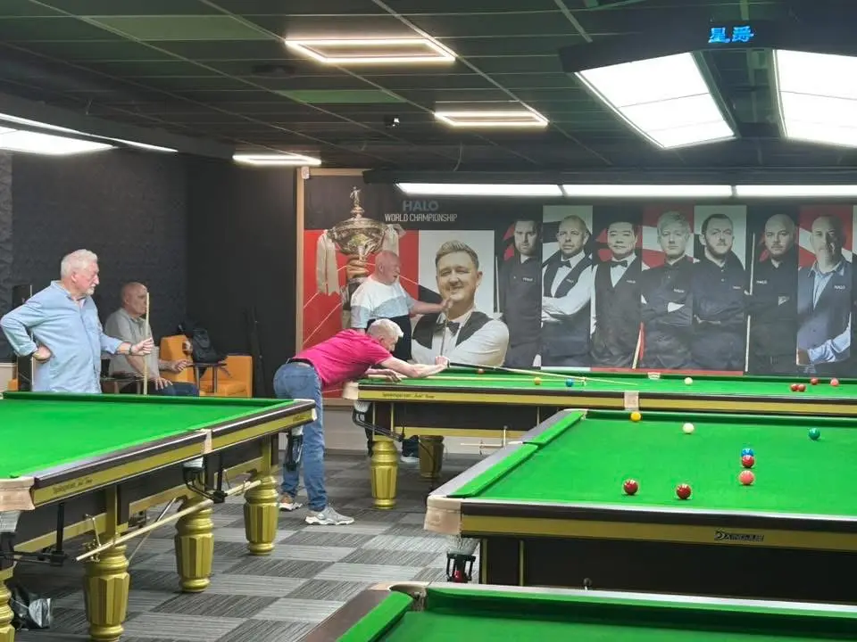 A player down on a shot with three others watching from behind the table